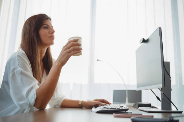istock Businesswoman sitting in her office, thinking and using computer, having coffee 1331033124