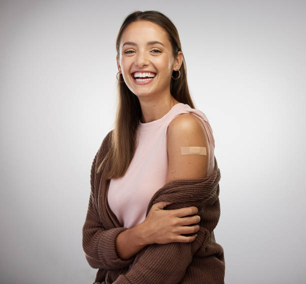 Shot of a young woman standing alone in the studio after getting vaccinated Why not just give it a shot? adhesive bandage photos stock pictures, royalty-free photos & images