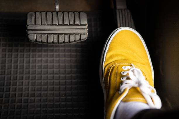 a man in yellow sneakers is stepping on the accelerator of a car. - pedal imagens e fotografias de stock