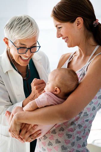 Mother holding baby for pediatrician doctor to examine. People healthcare concept