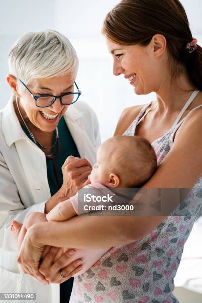 Mother Holding Baby For Pediatrician Doctor To Examine Stock Photo - Download Image Now