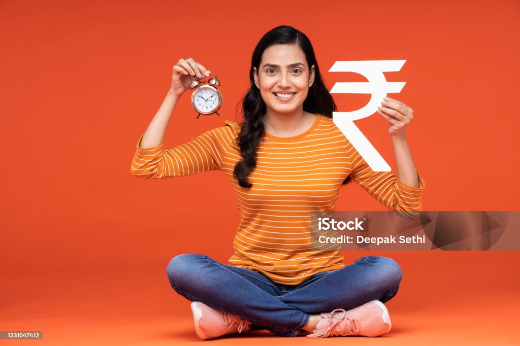 portrait of a young women sitting isolated over orange background Adult, young women backgrounds, India, Indian ethnicity, Holding Stock Photo