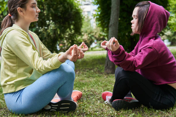 dziewczyny wykonujące ćwiczenia jogi na przyrodzie, siedząc w lotosie pozują na trawie - achondroplazja obrazy zdjęcia i obrazy z banku zdjęć