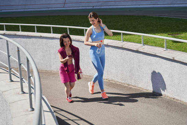 dziewczyna przechodząca przez tor stadionu ze swoją najlepszą przyjaciółką po bieganiu - achondroplazja obrazy zdjęcia i obrazy z banku zdjęć