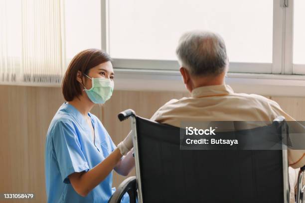 Young Asian Woman Nurse Explaining Information To Elderly Man Patient In Wheelchair With Friendly Smiley Face In The Hospital Young Assistance With Old People In The Elderly Care Place Stock Photo - Download Image Now