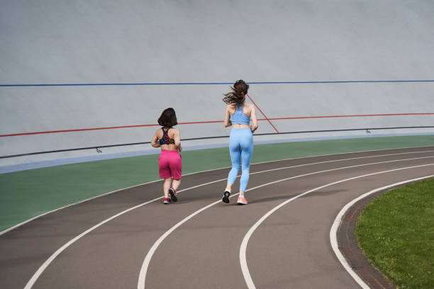 dziewczyny biegające na torze biegowym na stadionie miejskim w słoneczny poranek - achondroplazja obrazy zdjęcia i obrazy z banku zdjęć