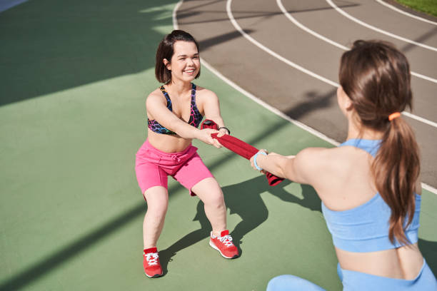 Girls standing in front of each other while tug of towel like a war Competition. High angle view of the two attractive girls standing in front of each other while tug of towel like a war at the stadium at the morning dwarf stock pictures, royalty-free photos & images