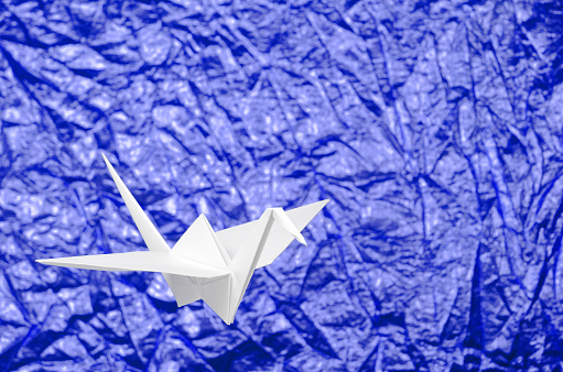 White origami photographed on blue background with shallow DOF.