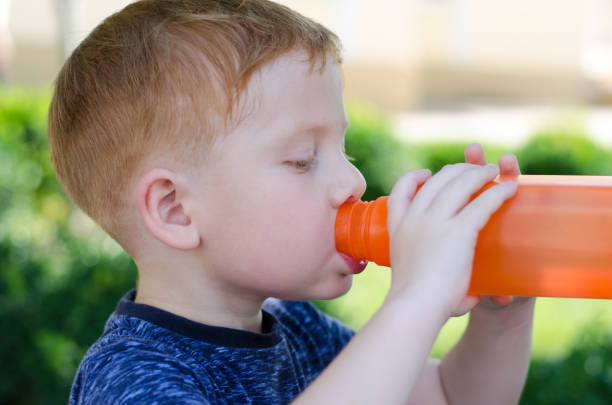 istock A red-haired 4-year-old boy is drinking water from a bottle, close-up. A child drinks water from a bottle on a hot summer day. 1331061232
