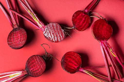 Halved common beet vegetable beetroot healthy plant also known as the table beet, garden beet, red beet, dinner beet or golden bee on red background