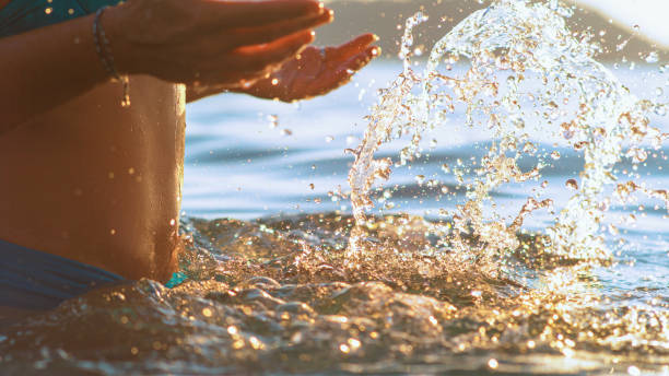 istock CLOSE UP: Unrecognizable woman in a blue bikini splashes sea water with hands. 1331064151