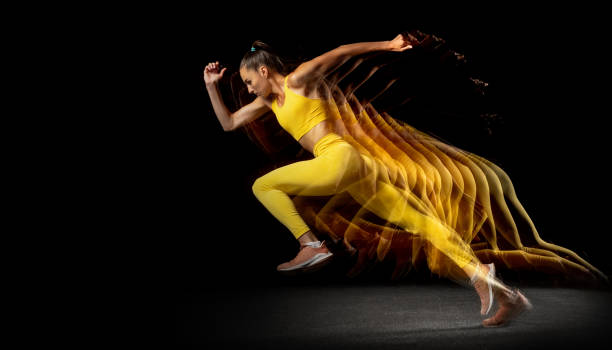 junge profi-athletin, die isoliert über schwarzen studiohintergrund in gemischten neonlichtern zur seite läuft. seitenansicht - stroboscopic image stock-fotos und bilder