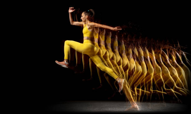 istock Side view. Young professional female athlete jumping high isolated over black studio background in mixed neon lights 1331064469