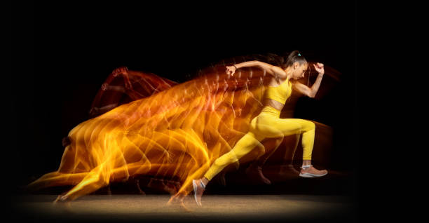młoda kobieta, zawodniczka biegająca na bok odizolowana na czarnym tle studia w mieszanych neonach. widok z boku - jumping women running vitality zdjęcia i obrazy z banku zdjęć