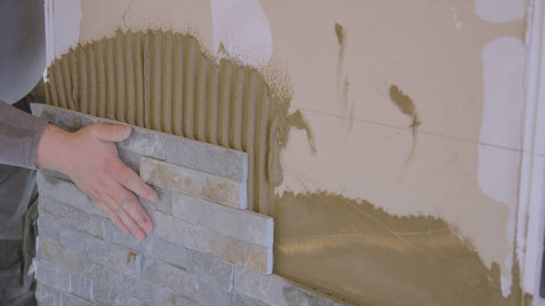 istock CLOSE UP: Builder presses a tile firmly against the wall covered in mortar. 1331064861