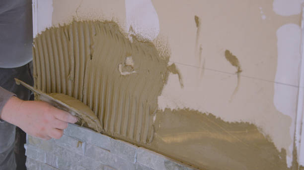 istock CLOSE UP: Contractor applies mortar on wall while laying natural stone tiles. 1331065577