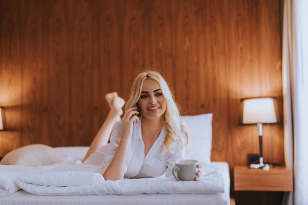 istock Happy womanl using a mobile phone while lying on the bed and drink morning coffee 1331065709