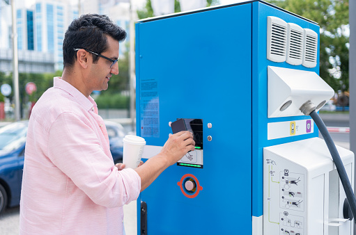Man Paying With Digital Wallet At Electric Vehicle Charging Station