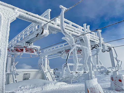 Empty chairlift station and benches at a shut down ski resort in the Slovenian mountains are covered in a layer of thick ice. Extreme weather condition cause an entire ski lift system to freeze over.