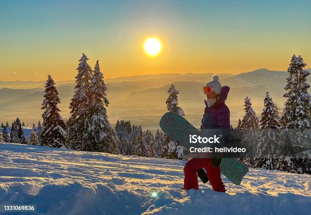 Close Up Young Female Snowboarder Hikes Up Ungroomed Snowy Slope At Sunset Stock Photo - Download Image Now