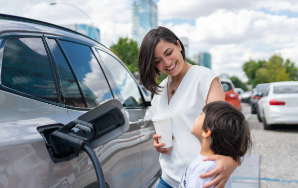 mujer y niño cargando coche eléctrico - vehículo eléctrico fotos fotografías e imágenes de stock