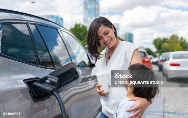 Woman And Child Charging Electric Car Stock Photo - Download Image Now - Electric Car, Electric Vehicle, Charging
