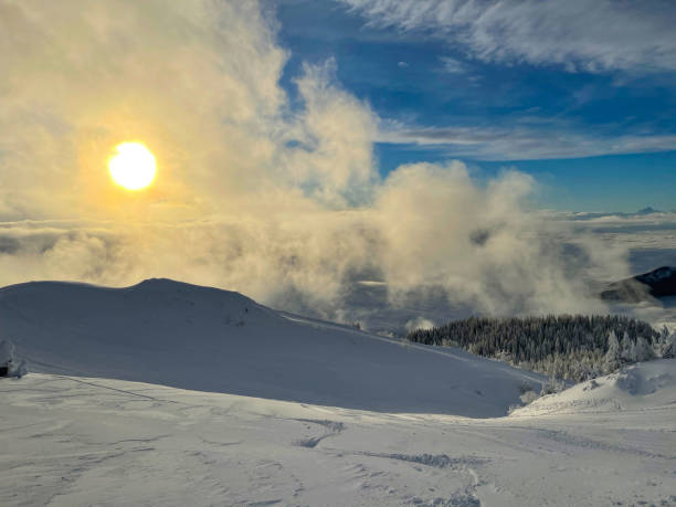 Golden winter morning sun rises above scenic backcountry covered in fresh snow. Golden winter morning sun rises above the scenic backcountry covered in fresh powder snow. Picturesque shot from the snowy mountaintop in rural part of Slovenia overlooking the wintry valley at sunset krvavec stock pictures, royalty-free photos & images