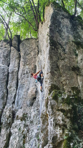 istock VERTICAL: Strong woman climbs up a difficult rocky wall on a perfect spring day. 1331070941
