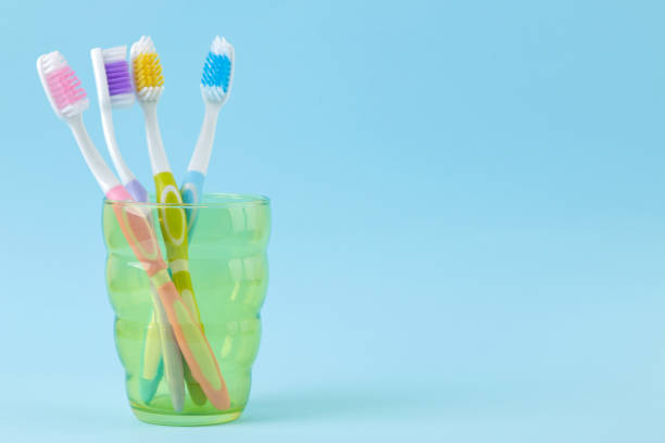 istock Oral hygiene. multi-colored toothbrush in a glass on a gentle blue background. space for text 1331071415