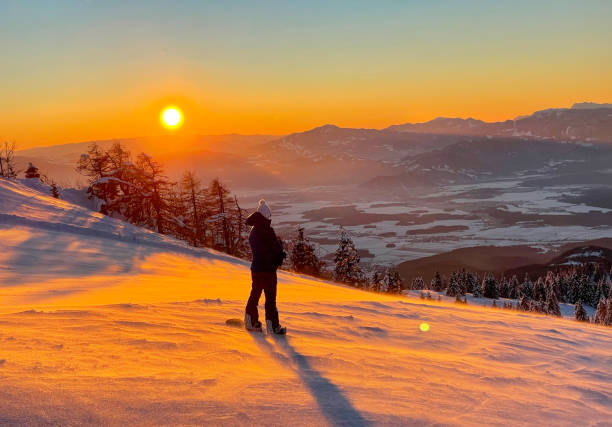 istock LENS FLARE: Female snowboarder observes the golden lit valley before her descent 1331072156