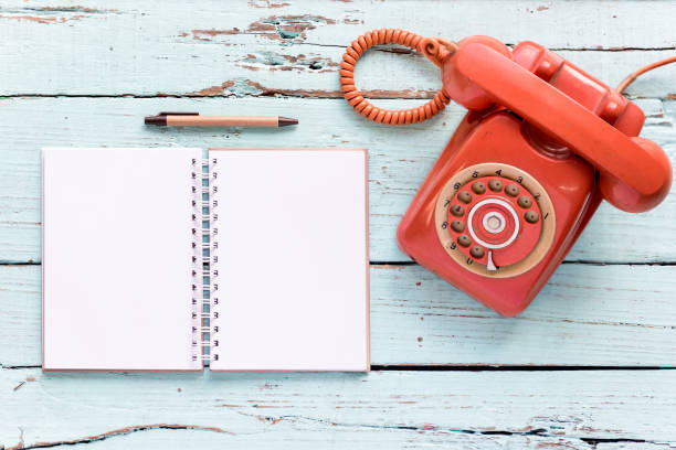 The diary blanks with retro telephone on the wooden table with copy space for text or your subject in the past.