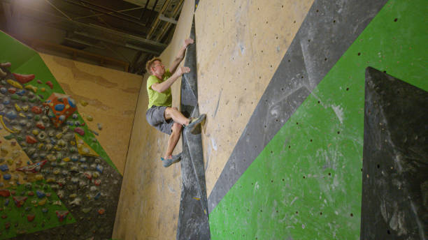 istock LOW ANGLE: Athletic man climbs up difficult climbing route at bouldering gym. 1331073042
