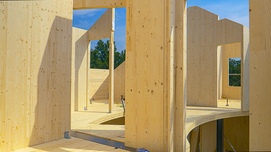 CLOSE UP: Beautiful hardwood real estate project is erected in the countryside. Glued-laminated timber house is being built in countryside. Aluminum ladders lie around the CLT house under construction