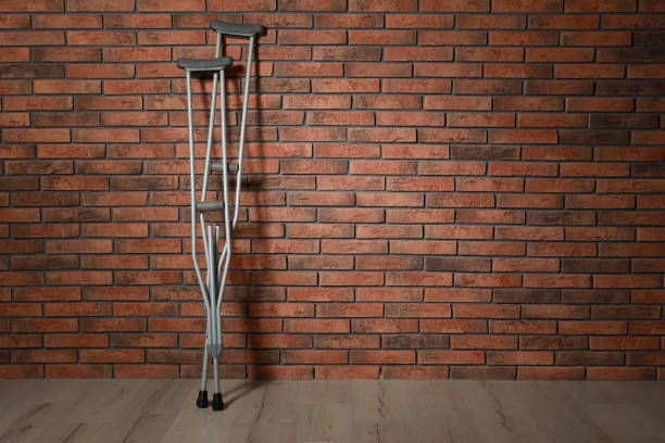 istock Pair of axillary crutches near red brick wall. Space for text 1331075761