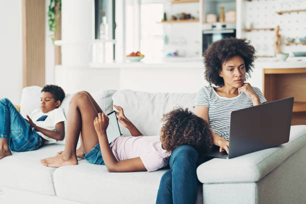 주변에서 모바일 장치를 사용하여 자녀와 함께 집에서 일하는 어머니 - laptop women child digital tablet 뉴스 사진 이미지