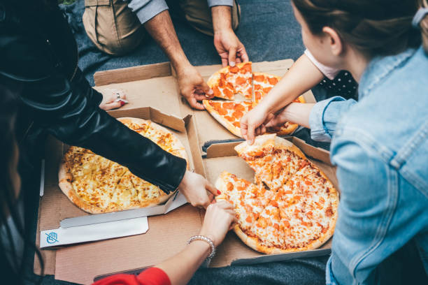 le persone con vista dall'alto afferrano fette di pizza dalla scatola al picnic all'aperto. - pizza foto e immagini stock