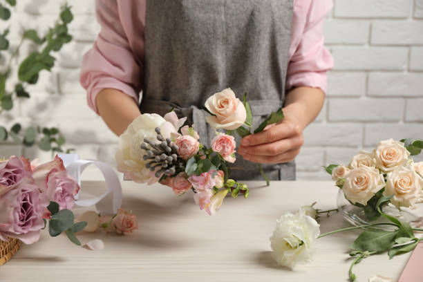 istock Florist creating beautiful bouquet at white table indoors, closeup 1331076748