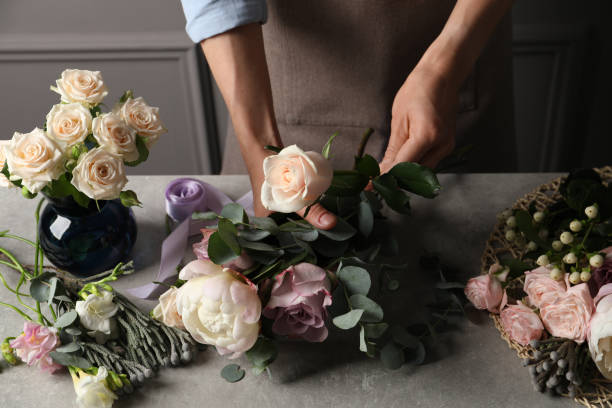 fiorista che crea un bellissimo bouquet al tavolo grigio chiaro all'interno, primo piano - florist foto e immagini stock