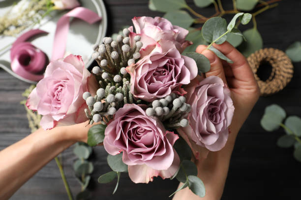 istock Florist creating beautiful bouquet at black wooden table, top view 1331077263