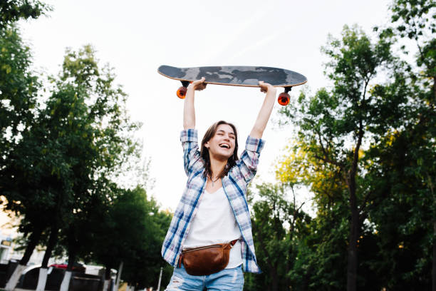 istock Cheerful happy woman throwing hand with a skateboard up. Low angle. 1331077315