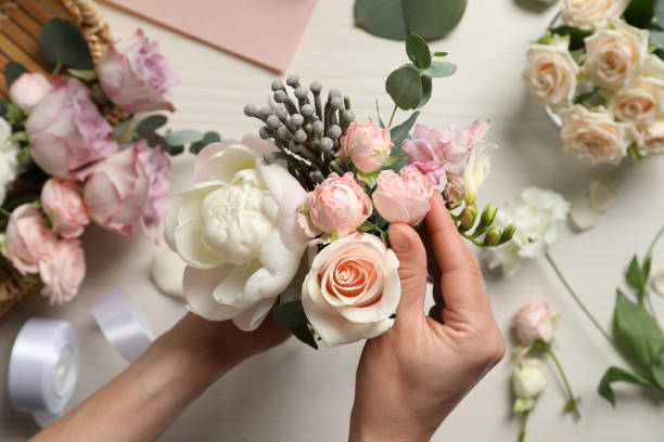 istock Florist creating beautiful bouquet at white table, top view 1331077647
