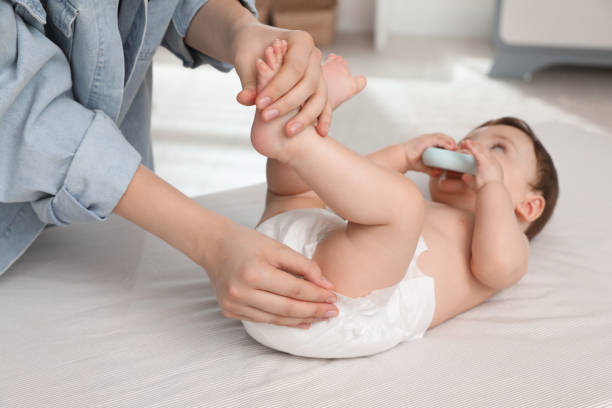 istock Mother changing baby's diaper on bed at home, closeup 1331078560