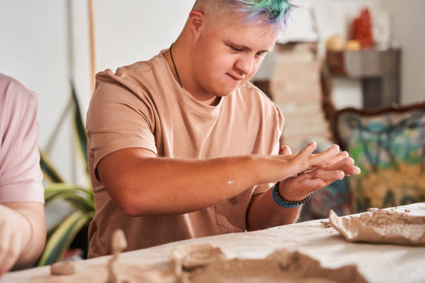 down syndrome boy with colored hair holding piece of clay and preparing new dish - downs syndrome work bildbanksfoton och bilder