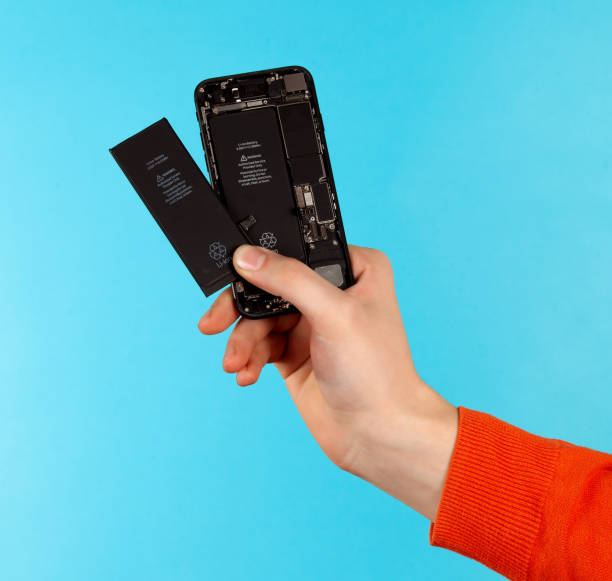 ręka trzyma telefon komórkowy, aby zastąpić naprawę baterii na niebieskim tle - screwdriver isolated blue work tool zdjęcia i obrazy z banku zdjęć