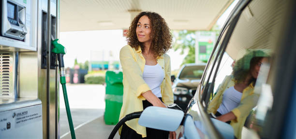 woman filling up at the petrol pump - petrol imagens e fotografias de stock