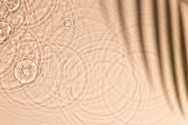 Beige water texture with ripples and transparent at sunlight. Backdrop for cosmetic or spa concept background. Copy space