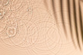 Beige water texture with ripples and transparent at sunlight. Backdrop for cosmetic or spa concept background. Copy space