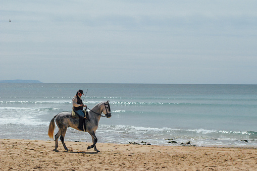 Man riding his horse on the beach in the autonomous community of Ansalusia, Spain. Concept of travel.