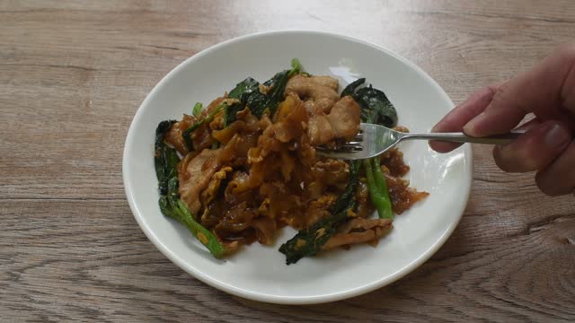 stir fried large rice noodles with slice fermenting pork and Chinese kale dressing black sweet soybean sauce stabbing by fork