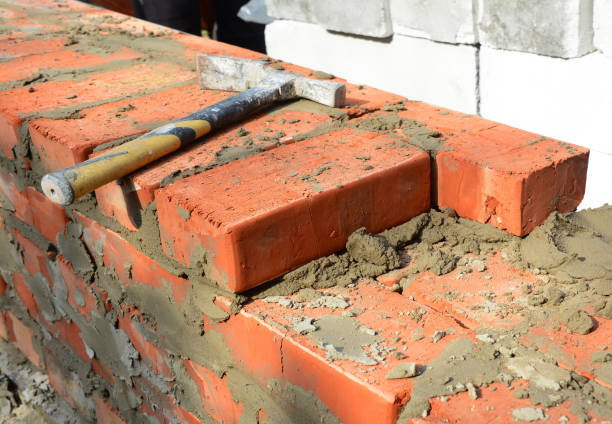 istock Masonry tools and equipment. A close-up of a masonry wall construction using a bricklayer's hammer, or a pick axe. 1331085664